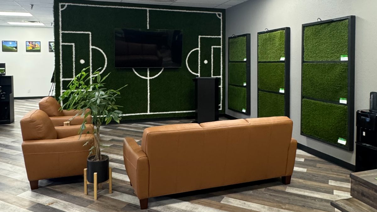 The Genesis showroom lounge with seating, a presentation screen on the turf feature wall, and sample boards
